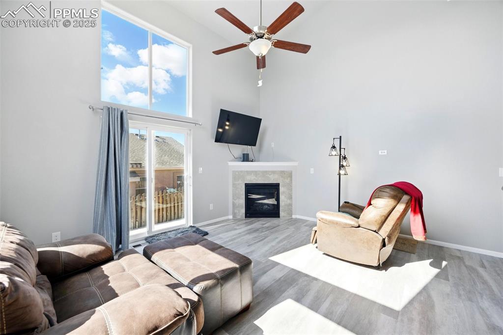 Image 10 of 46: Living area with a towering ceiling, a fireplace, wood finished floors, and