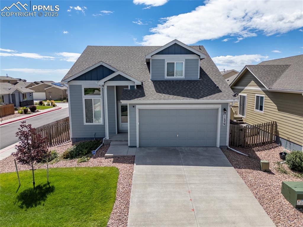 Image 27 of 46: View of front facade with roof with shingles, driveway, board and batten si