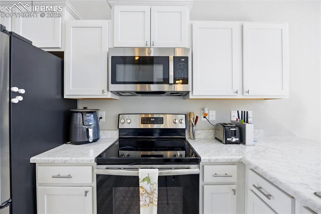 Image 4 of 46: Kitchen with appliances with stainless steel finishes and white cabinets