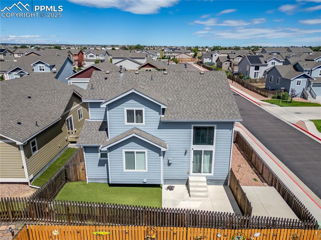 Image 40 of 46: Back of house featuring a shingled roof and a fenced backyard
