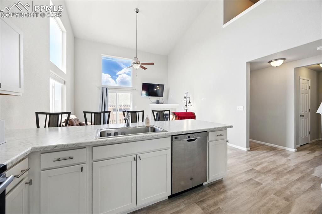 Image 6 of 46: Kitchen with white cabinets, stainless steel dishwasher, light countertops,