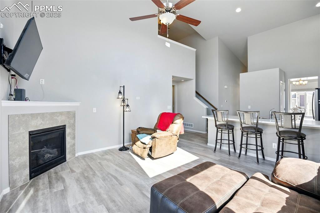 Image 7 of 46: Living area featuring high vaulted ceiling, light wood-style flooring, a gl