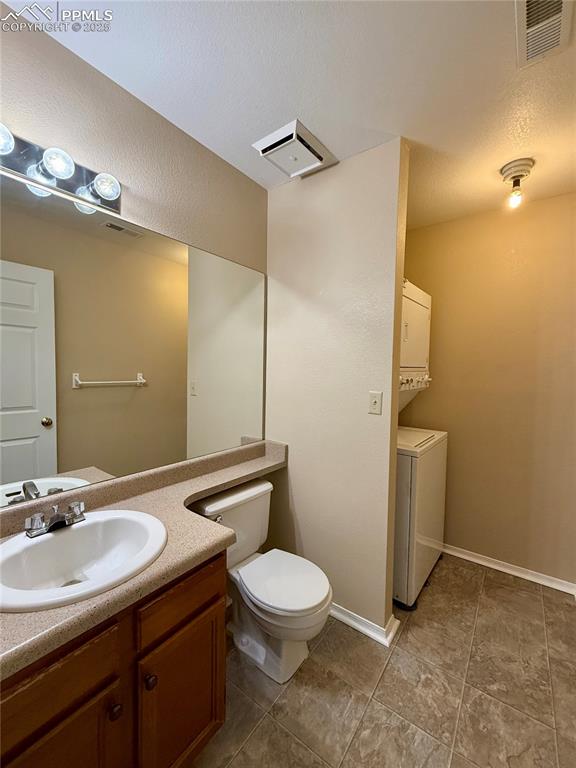 Image 8 of 23: Main level 1/2 bathroom with stackable washer and dryer.