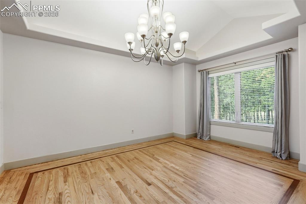 Image 11 of 50: Formal Elegant Dining Room featuring a tray ceiling, wood-flooring, chandel