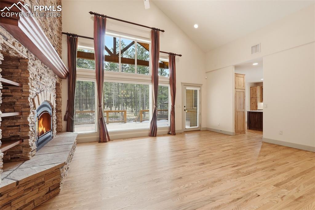 Image 13 of 50: Vaulted Living room with a fireplace stone hearth, wood floors, and prewire