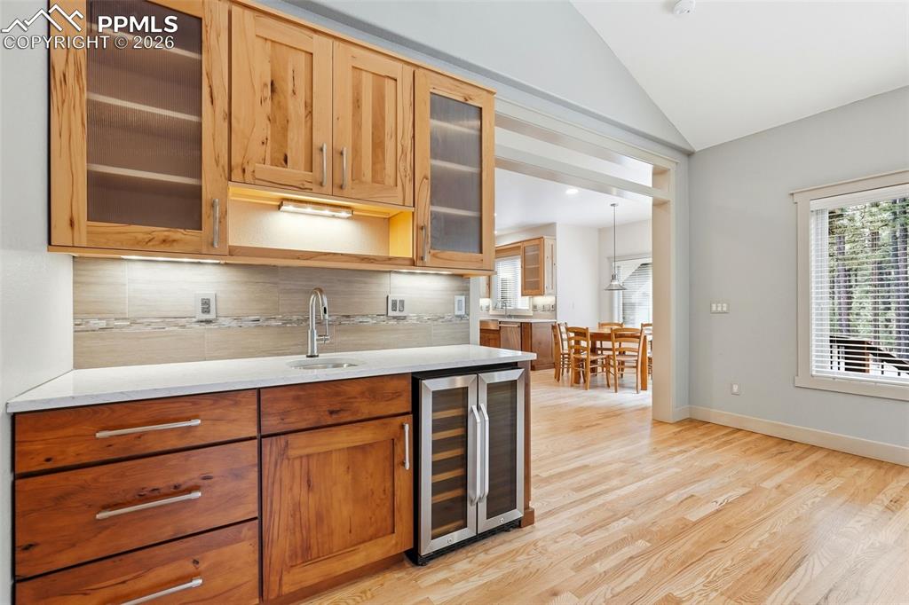 Image 17 of 50: Second bar area featuring glass fronted cabinets, wine cooler, tasteful bac