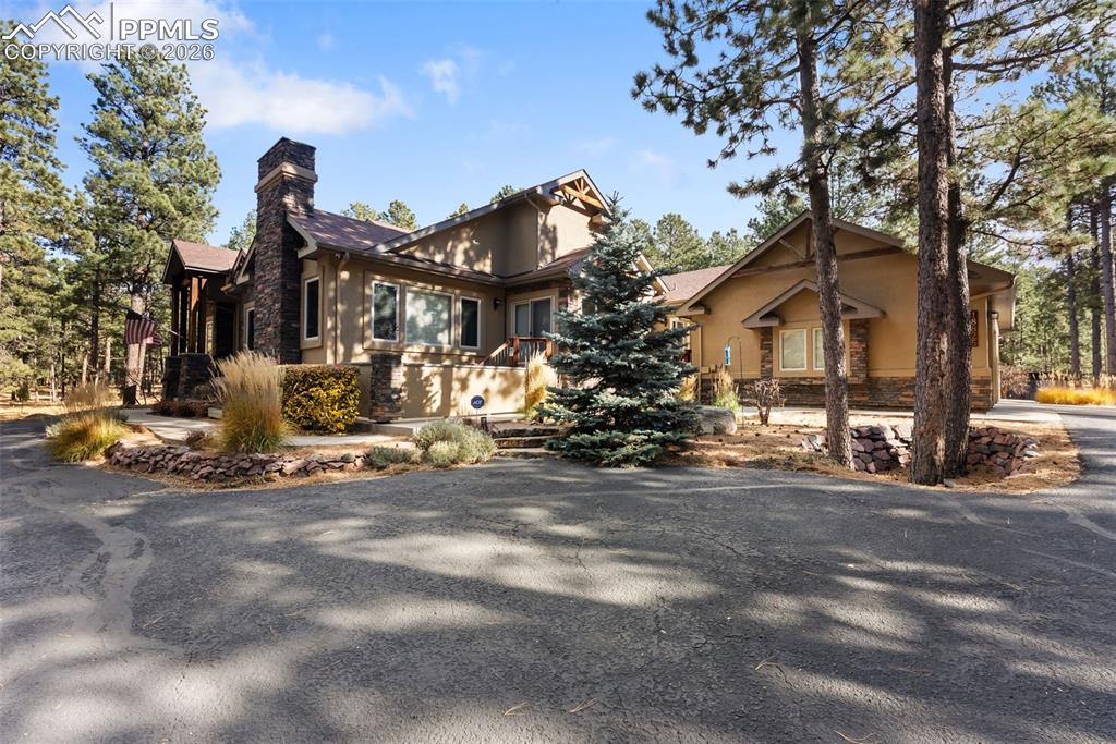 Image 2 of 50: Side View of front of home featuring trees and circular driveway