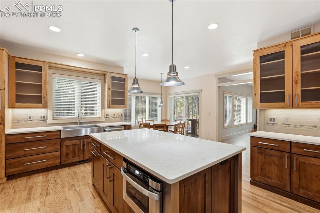Image 20 of 50: Kitchen featuring decorative backsplash, glass fronted cabinets, a center i