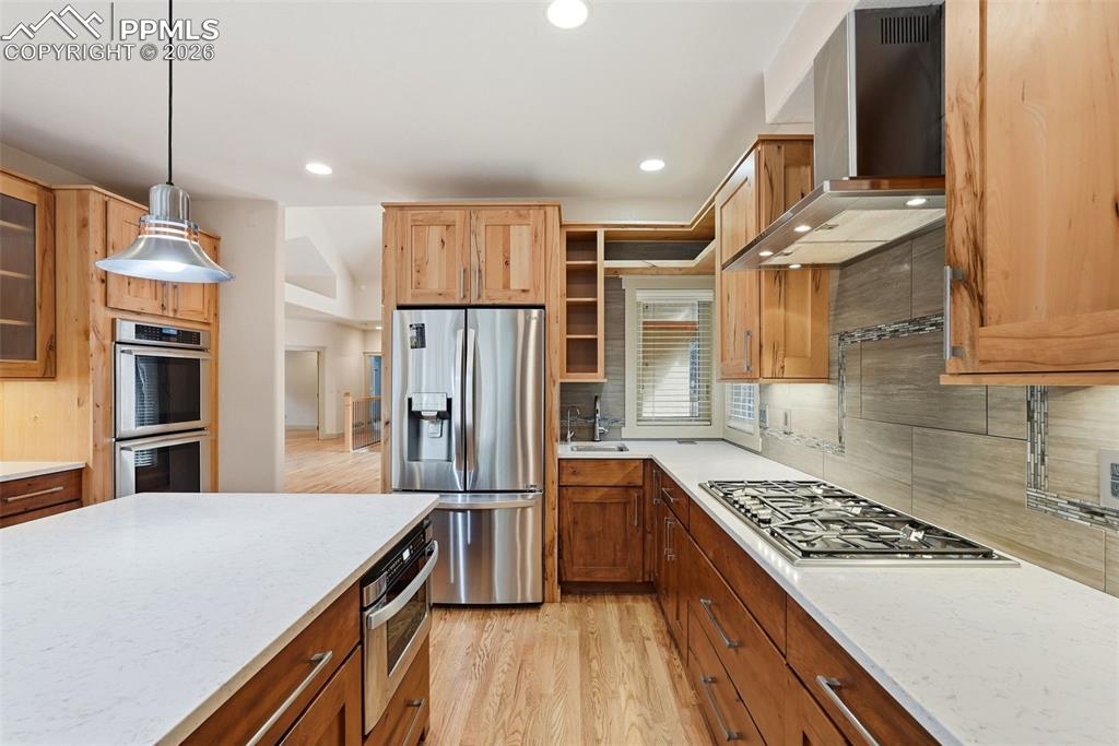 Image 21 of 50: Kitchen with stainless steel appliances, light wood flooring, stone counter
