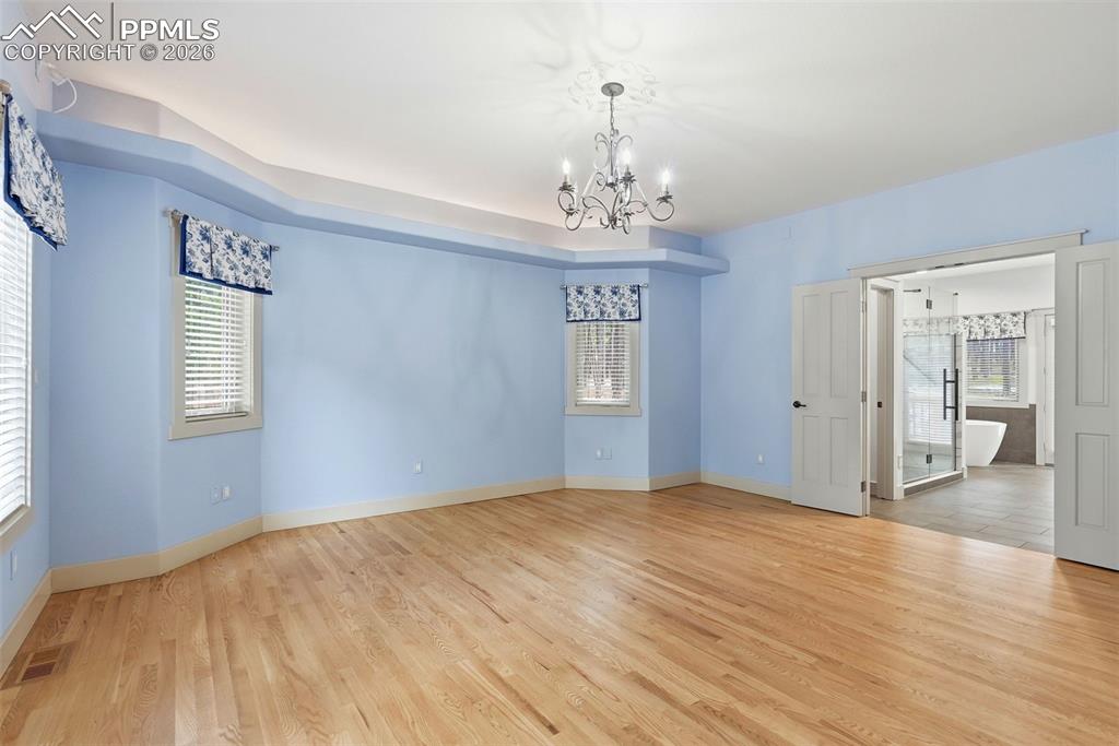 Image 29 of 50: Primary Bedroom suite with lot of natural light, hanging lights, wood floor