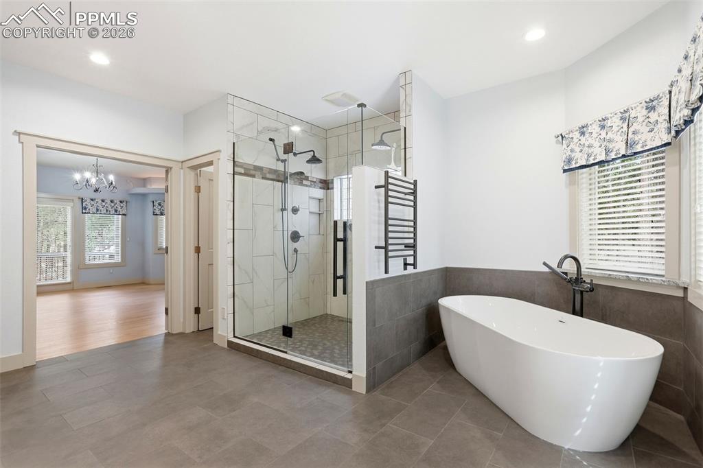 Image 35 of 50: Full bathroom with a freestanding tub, a shower stall, suspended lighting, 