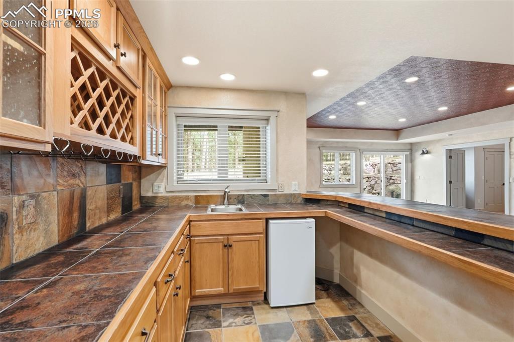 Image 38 of 50: 2nd Wet Bar area with stone finish flooring, glass fronted cabinets, recess