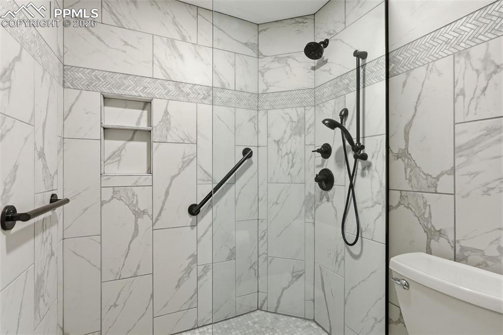 Image 43 of 50: Full bath featuring toilet and tiled shower