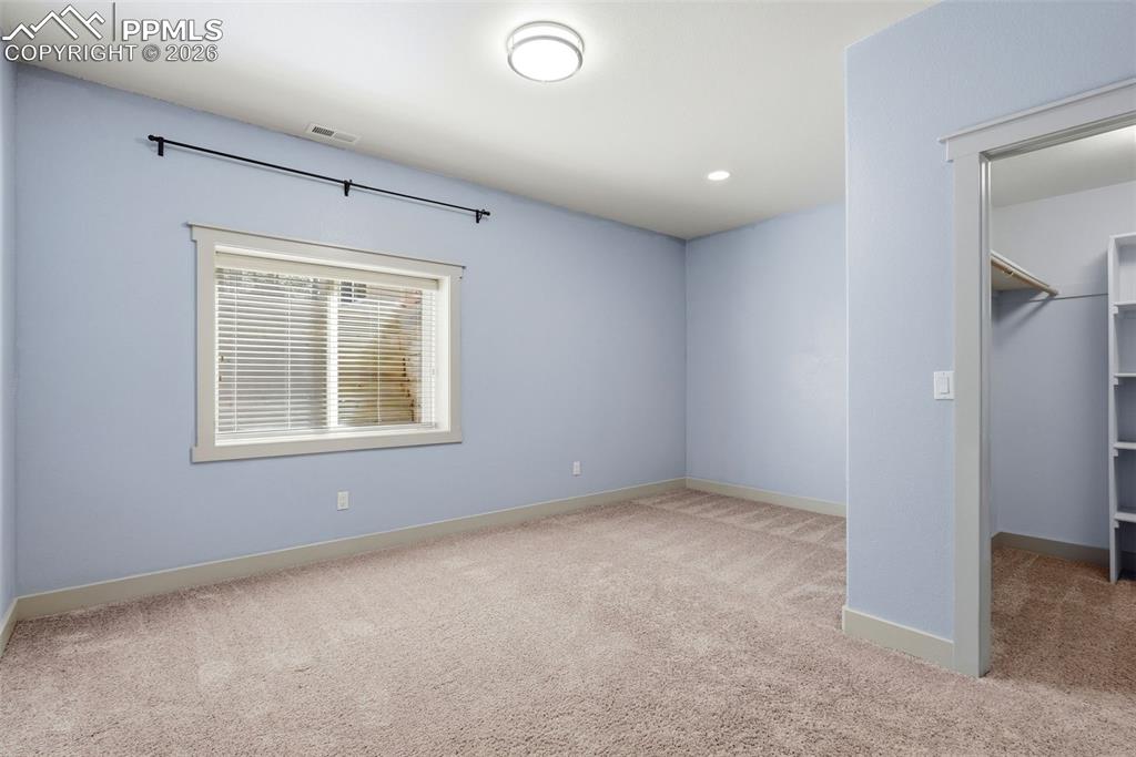 Image 48 of 50: 5th bedroom with light colored carpet and a walk in closet