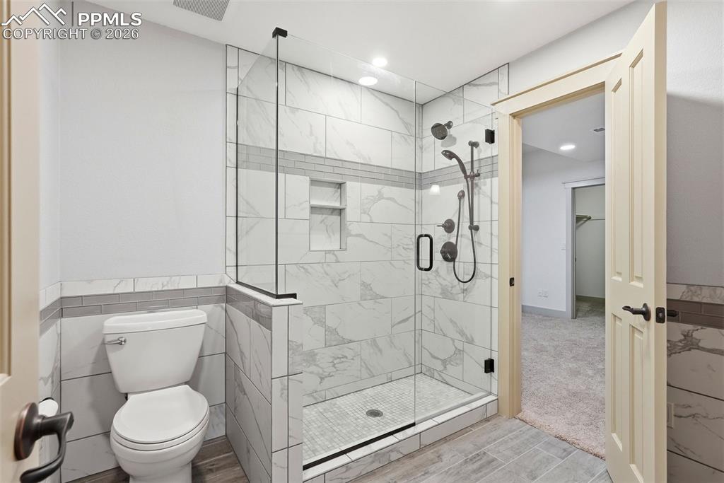 Image 50 of 50: Full bath with a shower stall, tile walls, wood finish floors, recessed lig