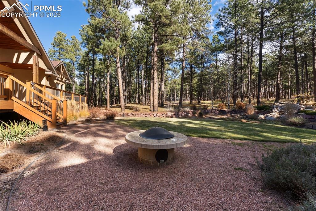 Image 9 of 50: View of yard featuring a fire pit and a patio area, sod and water feature