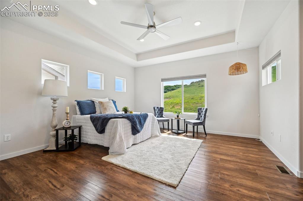 Image 17 of 30: Upper level Primary Bedroom with tray ceiling, lighted ceiling fan, two clo