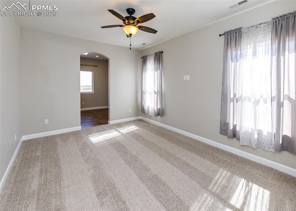 Image 16 of 27: Spacious primary bedroom with arched door detail with a peek into the bonus