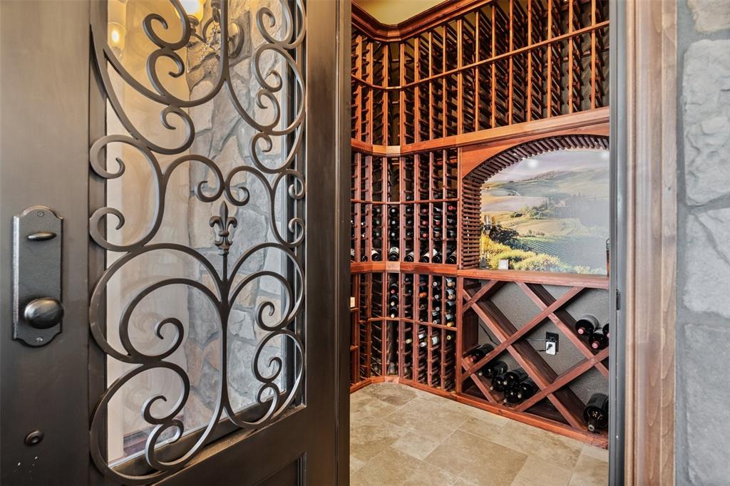 Image 15 of 50: Custom wine room behind an elegant wrought-iron door.