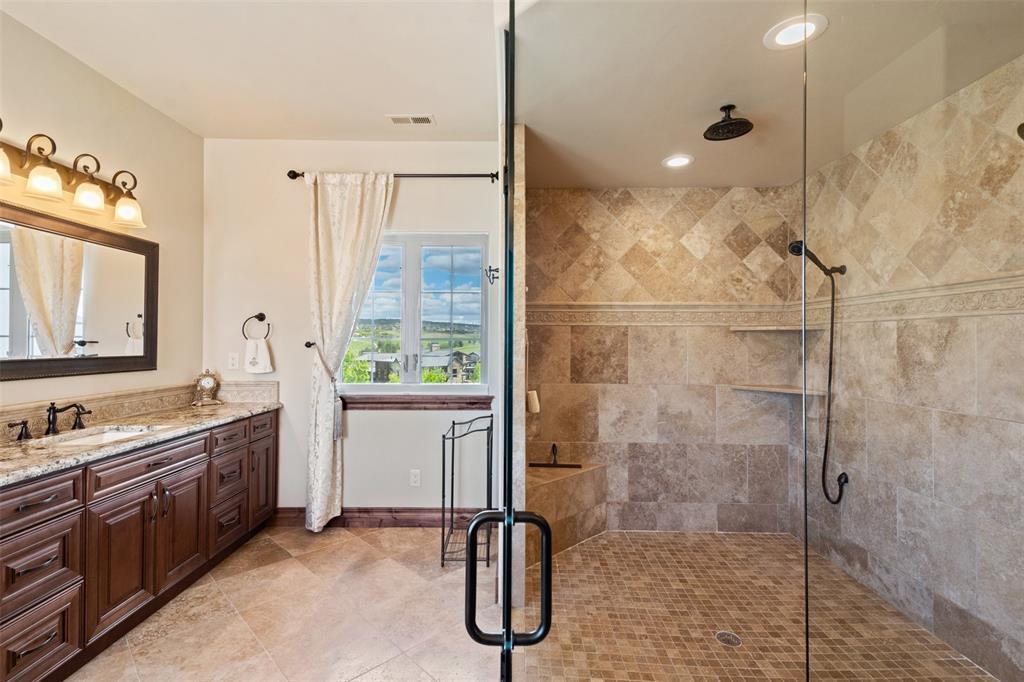 Image 27 of 50: Spacious zero entry spa shower with multiple showerheads and a bench, paire