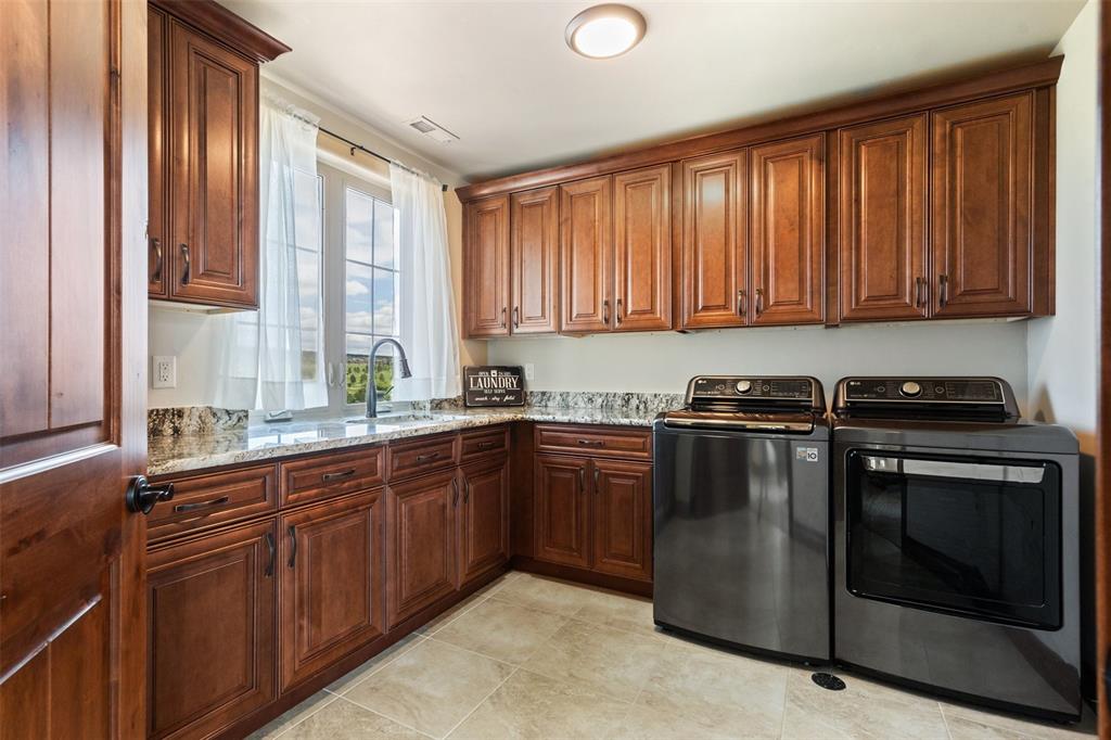 Image 31 of 50: Bright laundry room offering ample workspace and generous cabinet storage