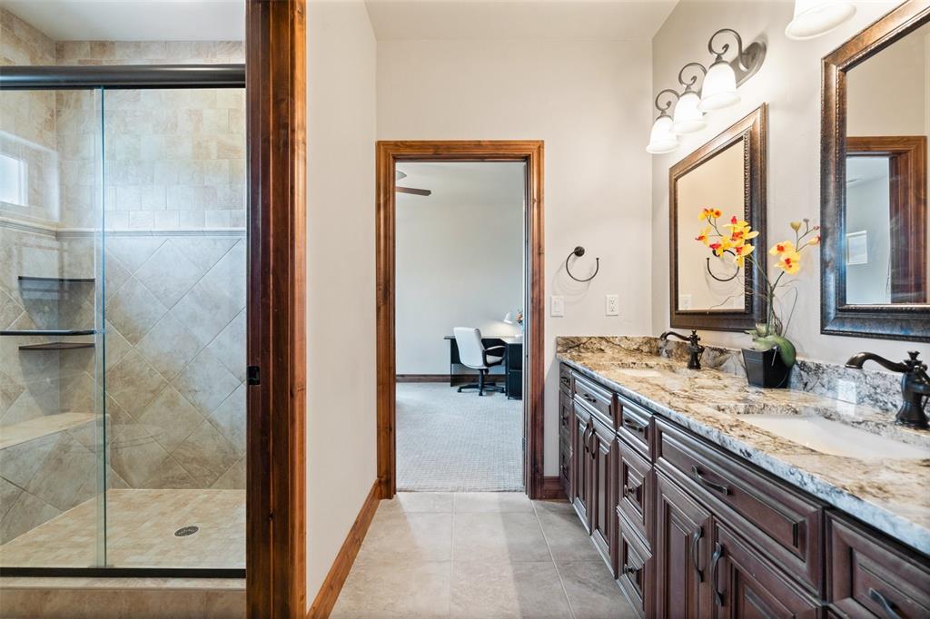 Image 33 of 50: Upper-level shared bath with granite double vanity and spacious walk-in sho
