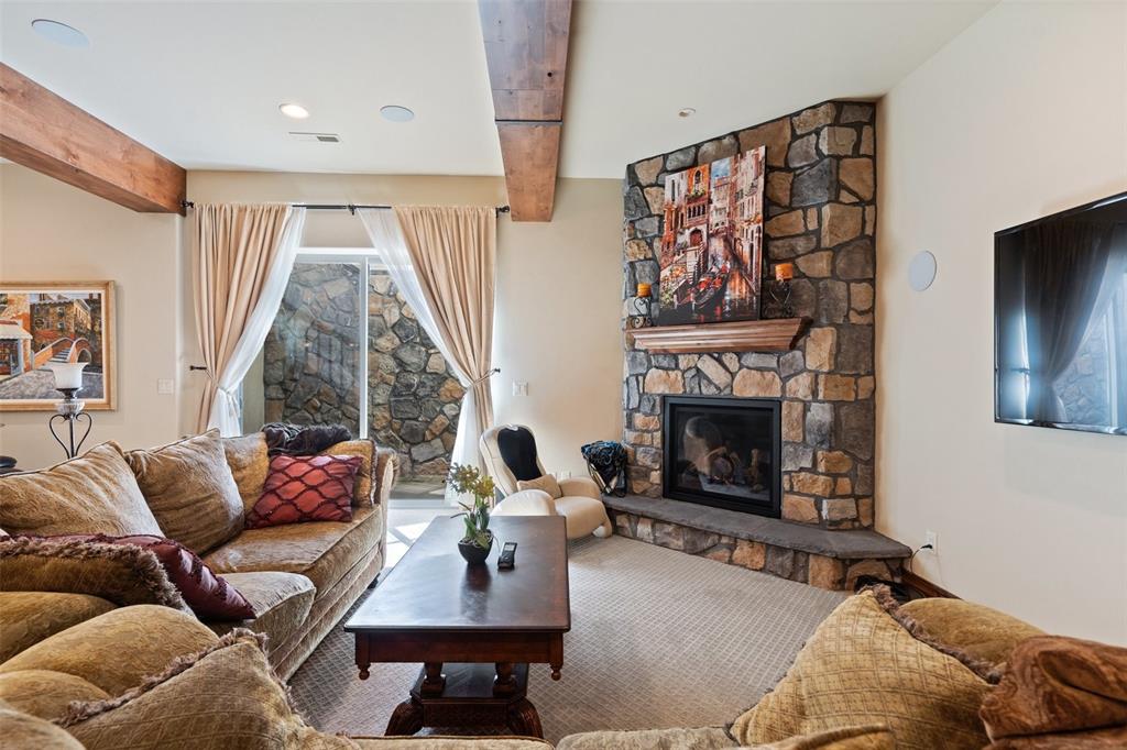 Image 37 of 50: Inviting lower-level living area featuring a floor-to-ceiling stone firepla