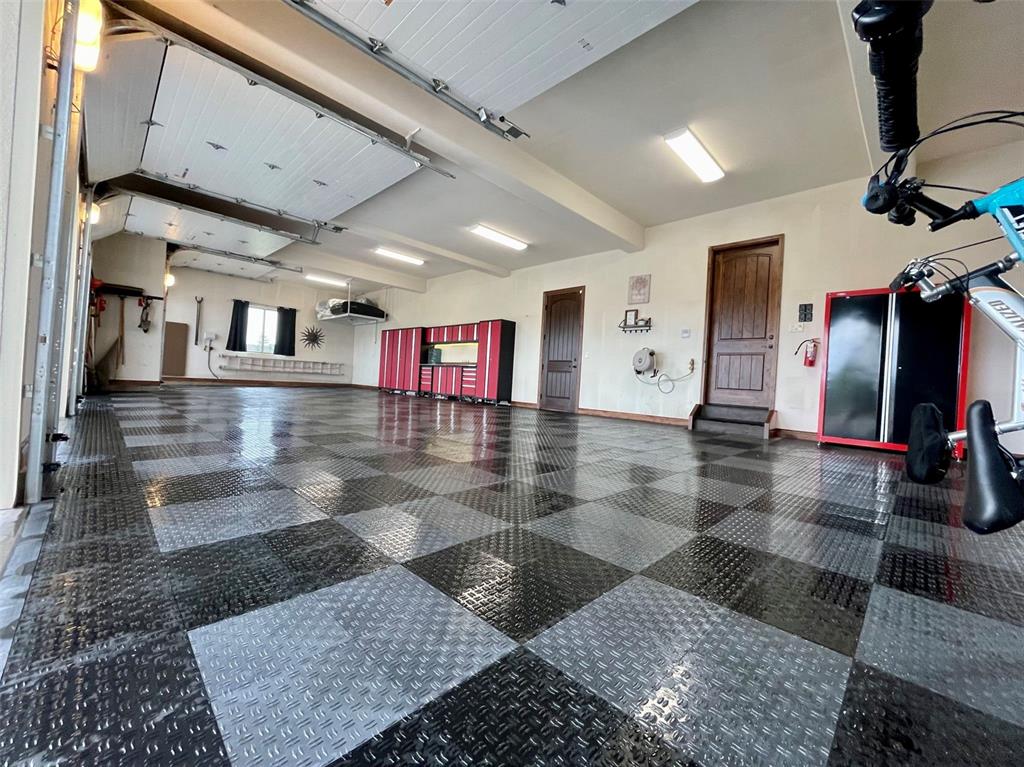 Image 44 of 50: Oversized four-car garage with custom flooring and built-in storage.