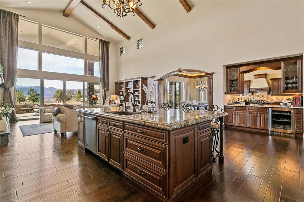 Image 5 of 50: Open-concept kitchen framed by a soaring cathedral ceiling with custom beam