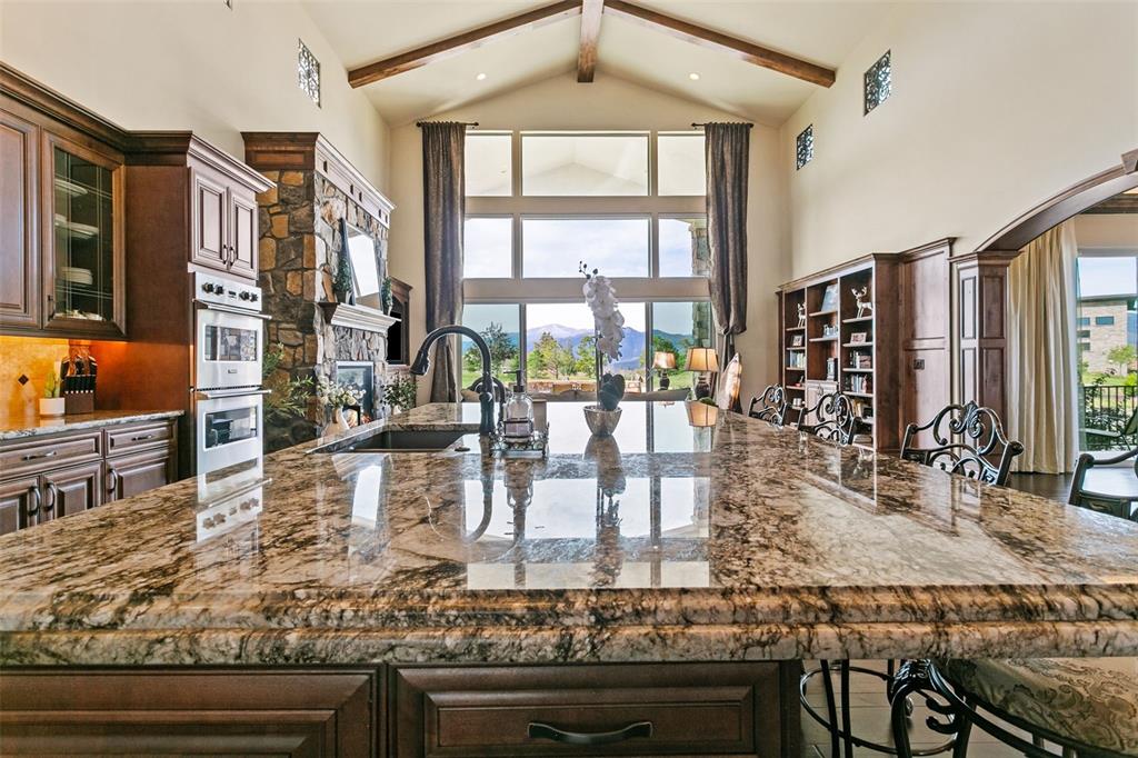 Image 6 of 50: Granite island looking into floor to ceiling window and views