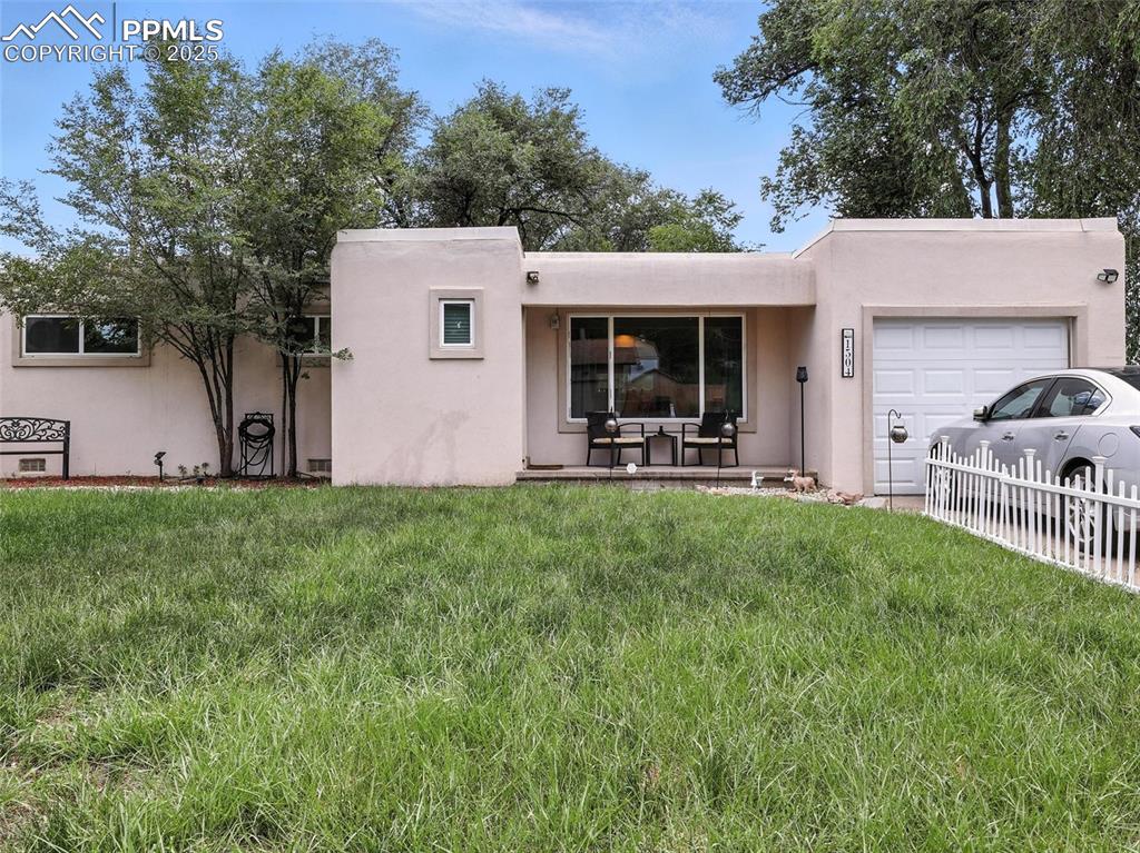 Caption: Pueblo-style home featuring stucco siding and a garage