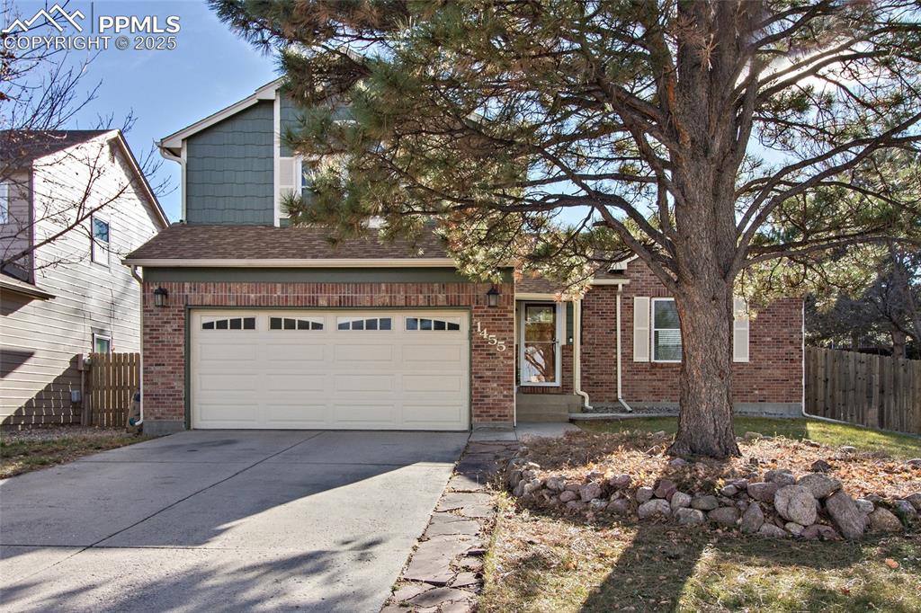 Caption: View of front of property with driveway, brick siding, a garage, and a shingled roof