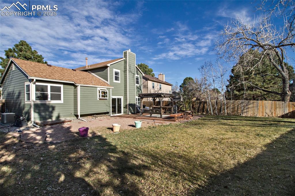 Image 11 of 43: Rear view of house featuring a fenced backyard, a pergola, a wooden deck, a