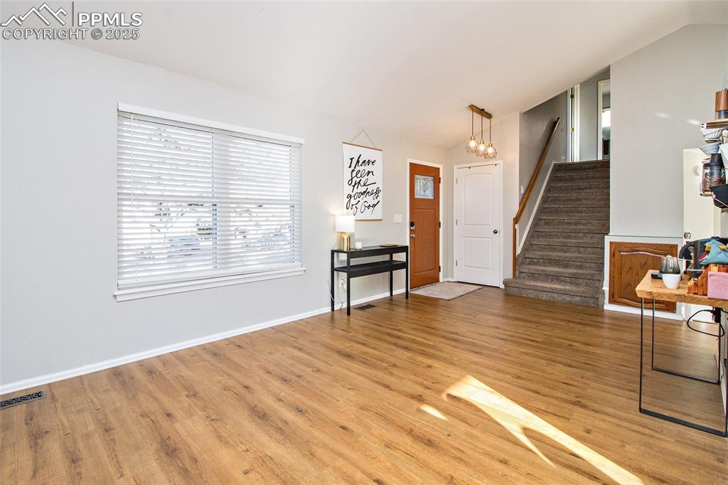 Image 17 of 43: Living area with vaulted ceiling, light wood finished floors, and stairs