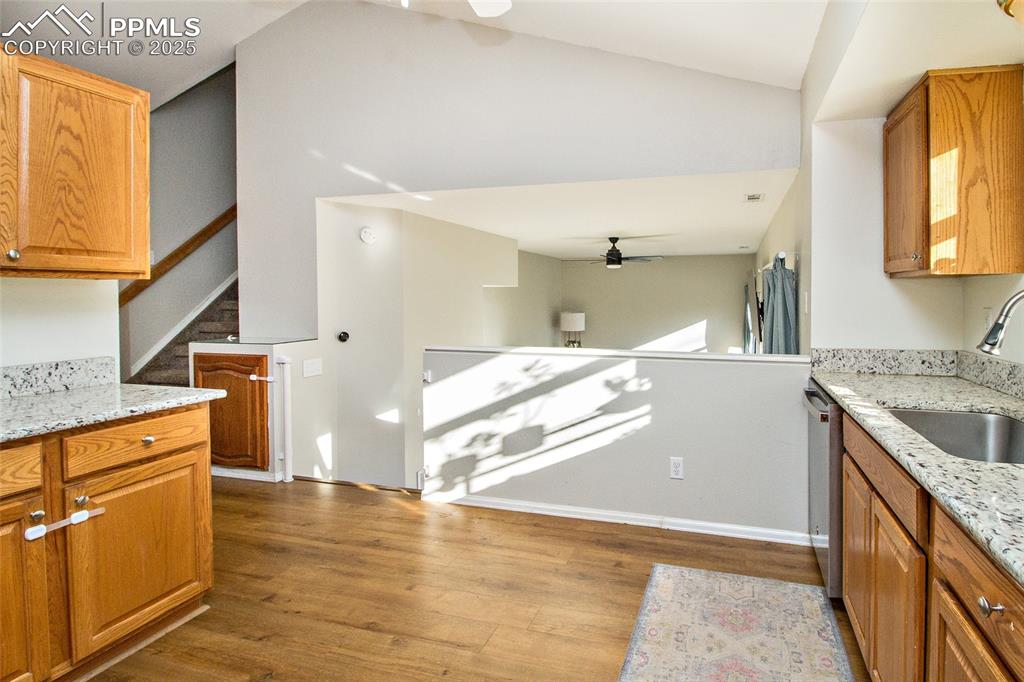 Image 22 of 43: Kitchen featuring light stone counters, brown cabinets, ceiling fan, light 