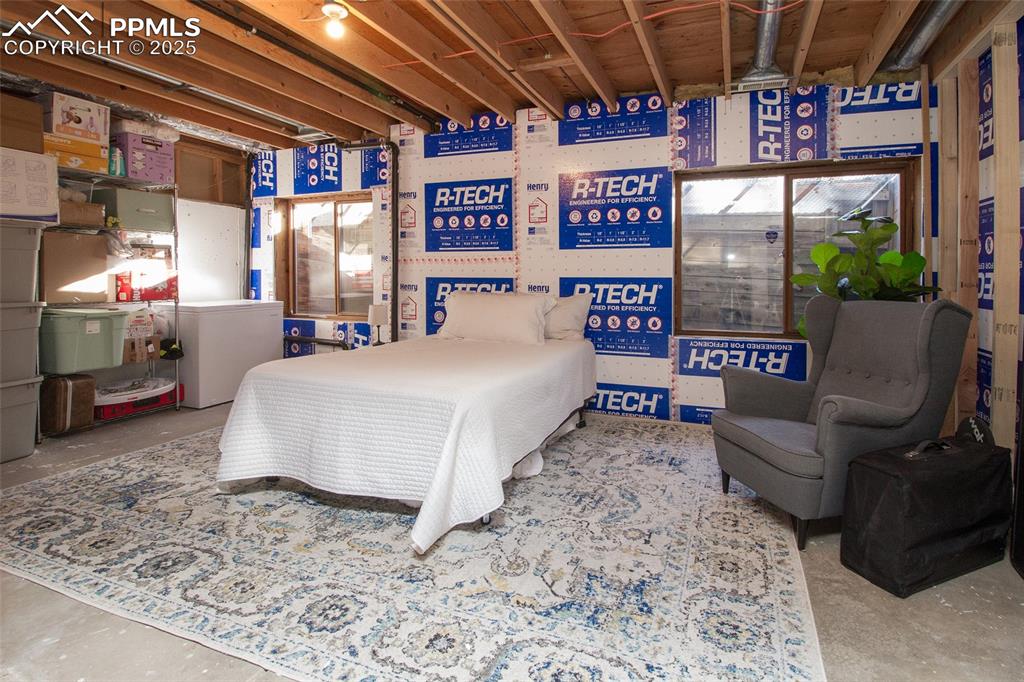 Image 32 of 43: Bedroom featuring unfinished concrete flooring and white refrigerator