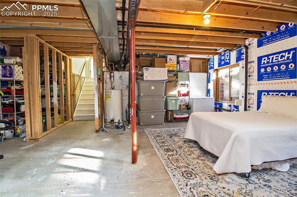 Image 33 of 43: Unfinished below grade area featuring heating unit, water heater, and stair