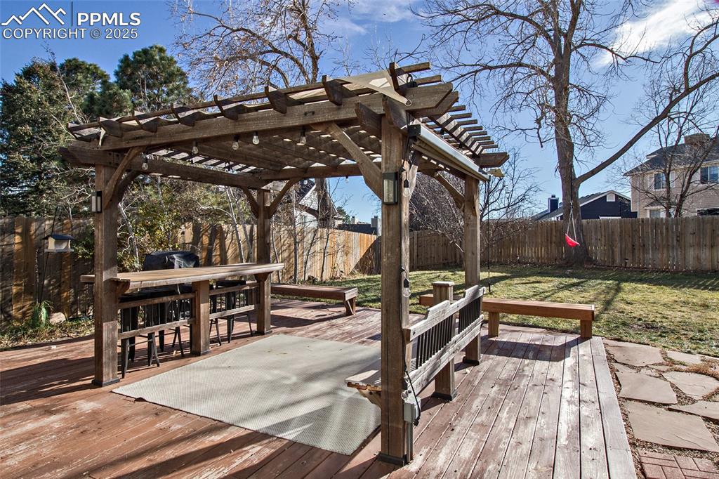 Image 4 of 43: Wooden terrace with a fenced backyard and grilling area