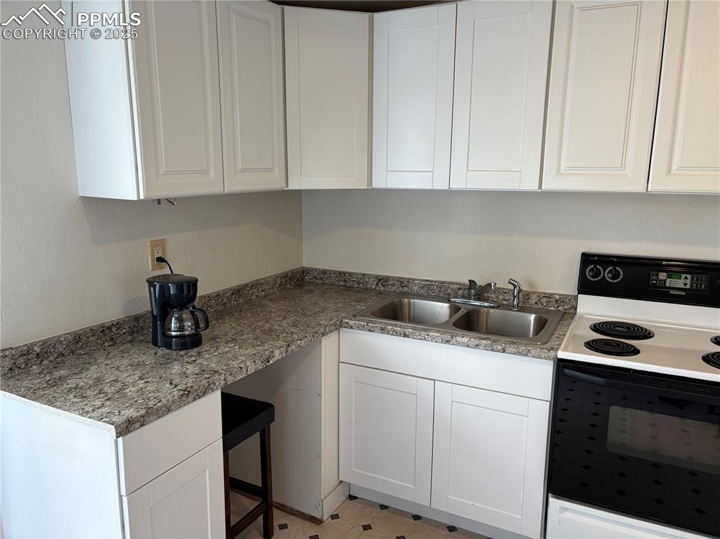 Image 4 of 8: Kitchen with electric range oven and white cabinets