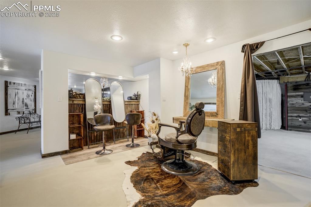 Image 21 of 50: Sitting room with concrete flooring, a chandelier, and recessed lighting