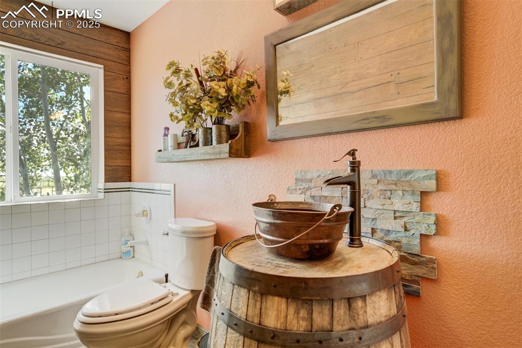 Image 32 of 50: Bathroom with a textured wall and a bath