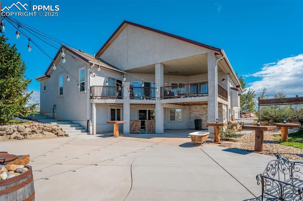Image 37 of 50: Back of property featuring stucco siding, a patio area, a balcony, and ston