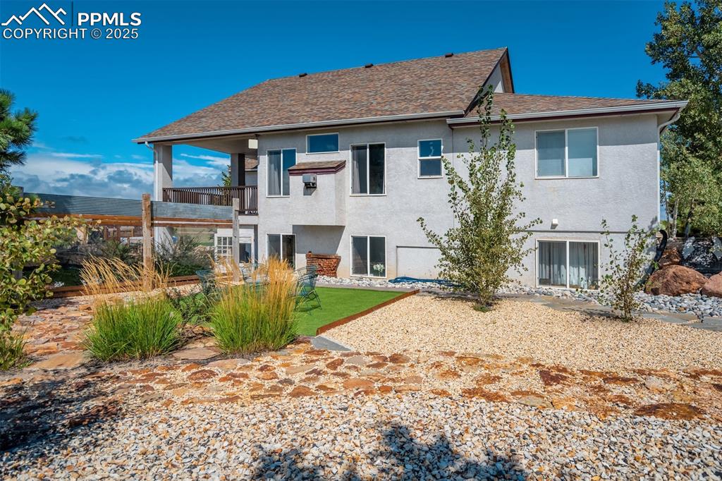 Image 38 of 50: Rear view of house with a balcony, stucco siding, a patio, a lawn, and a sh