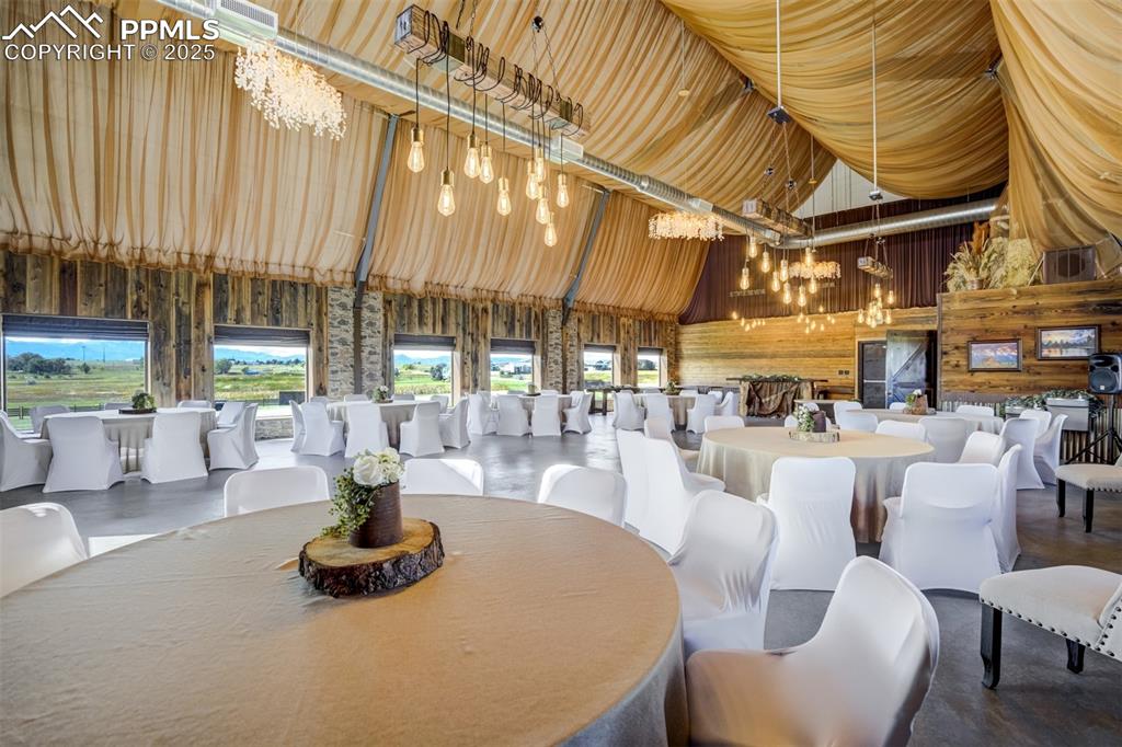 Image 45 of 50: Dining space featuring a chandelier, finished concrete floors, and high vau