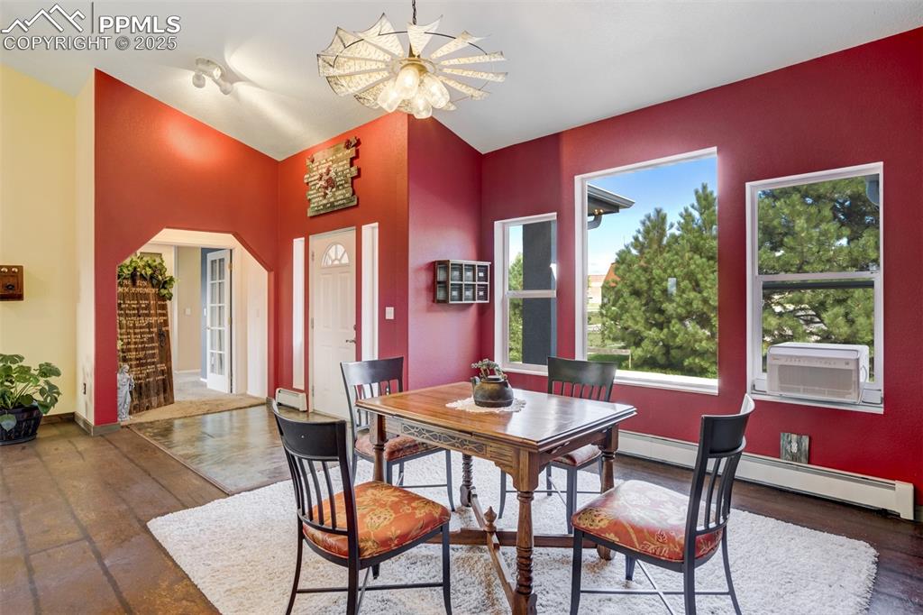 Image 7 of 50: Dining space featuring baseboard heating, arched walkways, dark wood-style 