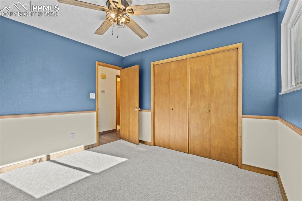 Image 23 of 42: Unfurnished bedroom with carpet floors, a ceiling fan, a closet, and a text