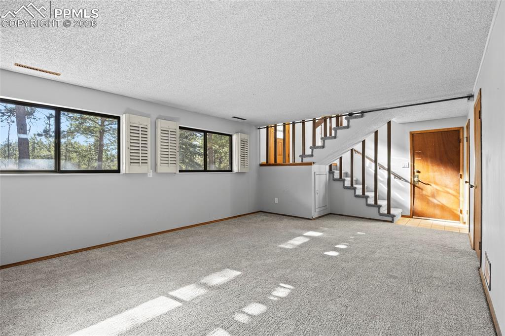 Image 26 of 42: Basement with a textured ceiling, carpet, and stairway