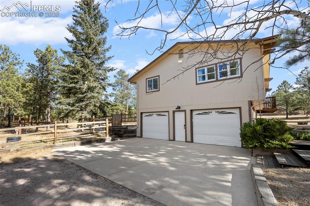 Image 29 of 42: View of side of home featuring concrete driveway and a garage