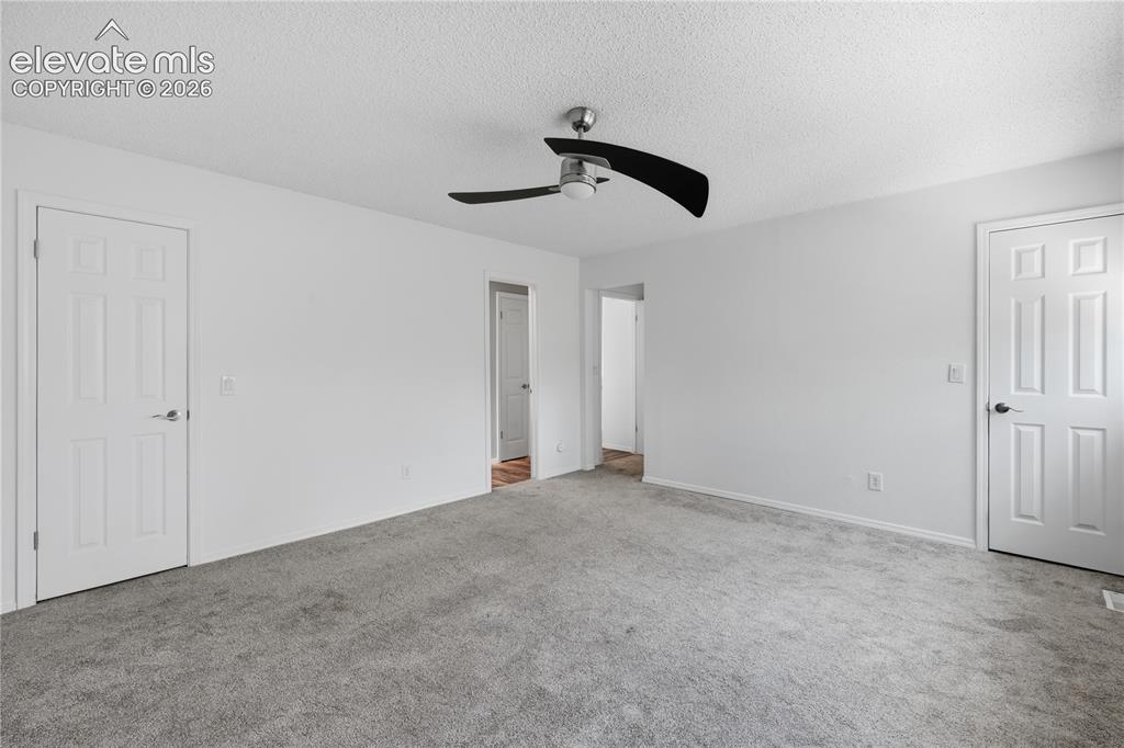 Image 10 of 15: Primary bedroom looking towards double closet doors and bathroom door