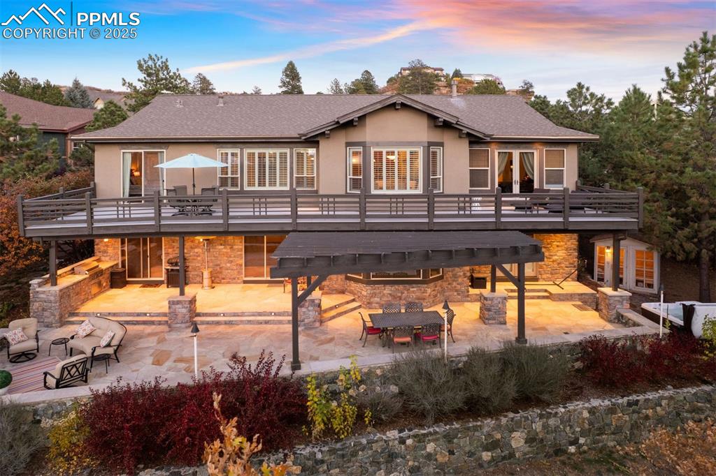 Image 16 of 50: Back of house at dusk featuring a patio, outdoor dining space, a deck, and 